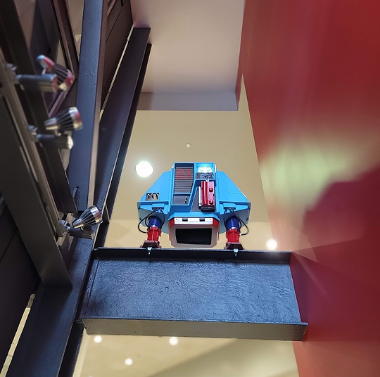 A robot is perched above a doorway.
