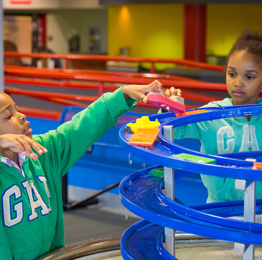 Two kids play with water at the Kamin Science Center.