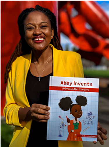 An author holds the book titled Abby Invents.