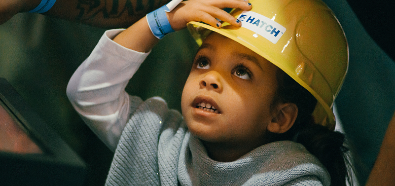 A small child wears a hard hat.