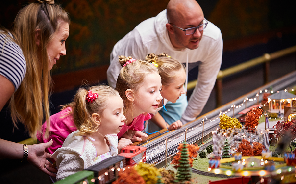 A family of two adults and three children look at the Miniature Railroad & Village