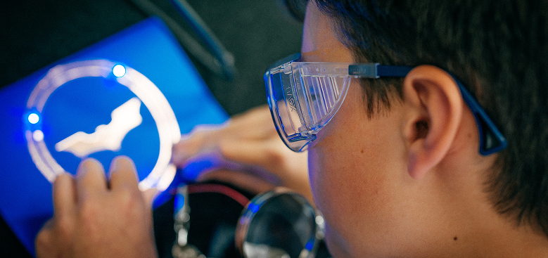A boy wears safety goggles and works on a project.