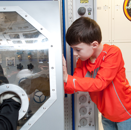 A young boy in a red shirt interacts with an exhibit at the Kamin Science Center