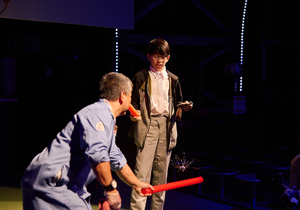 An adult and child on stage for a science demonstration.