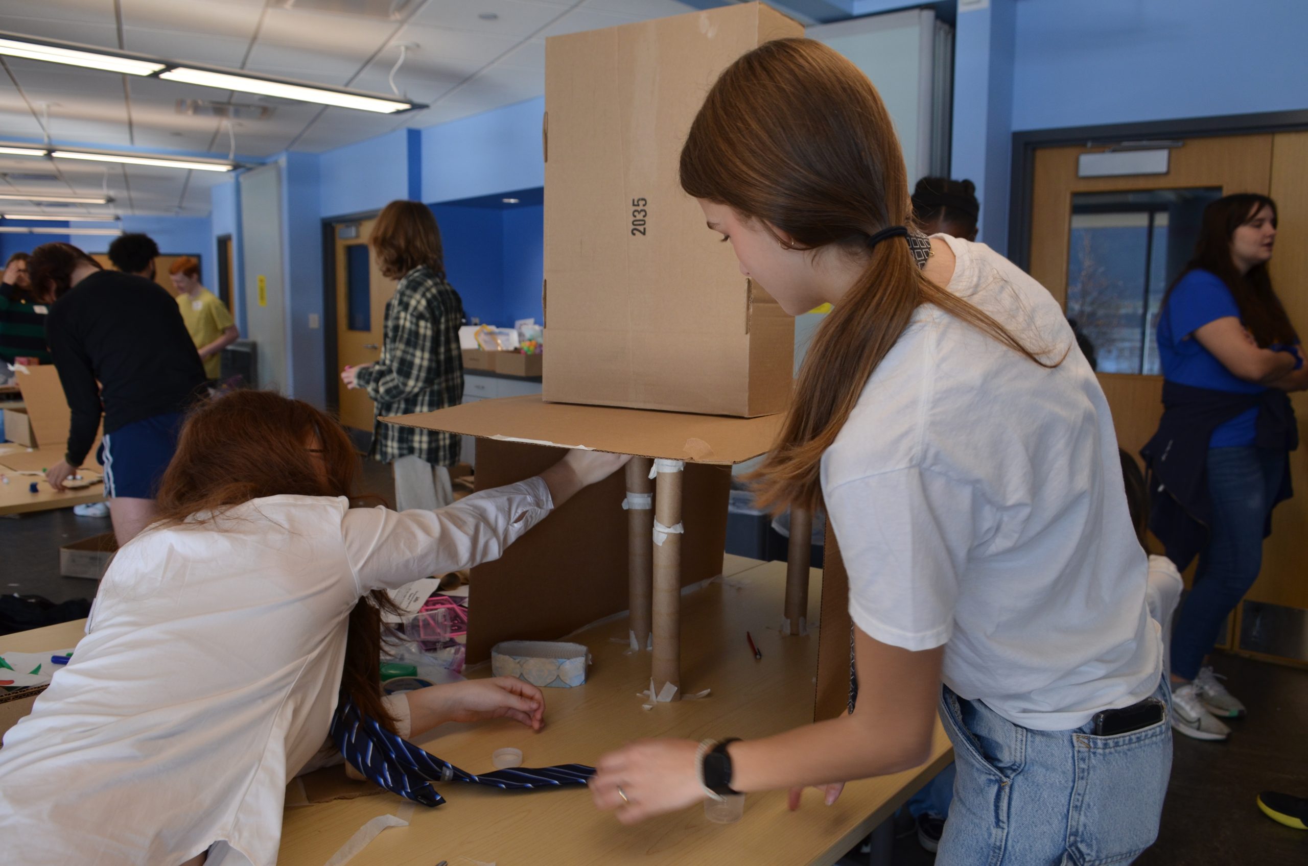 Two teenage girls putting the finishing touches on their science project.