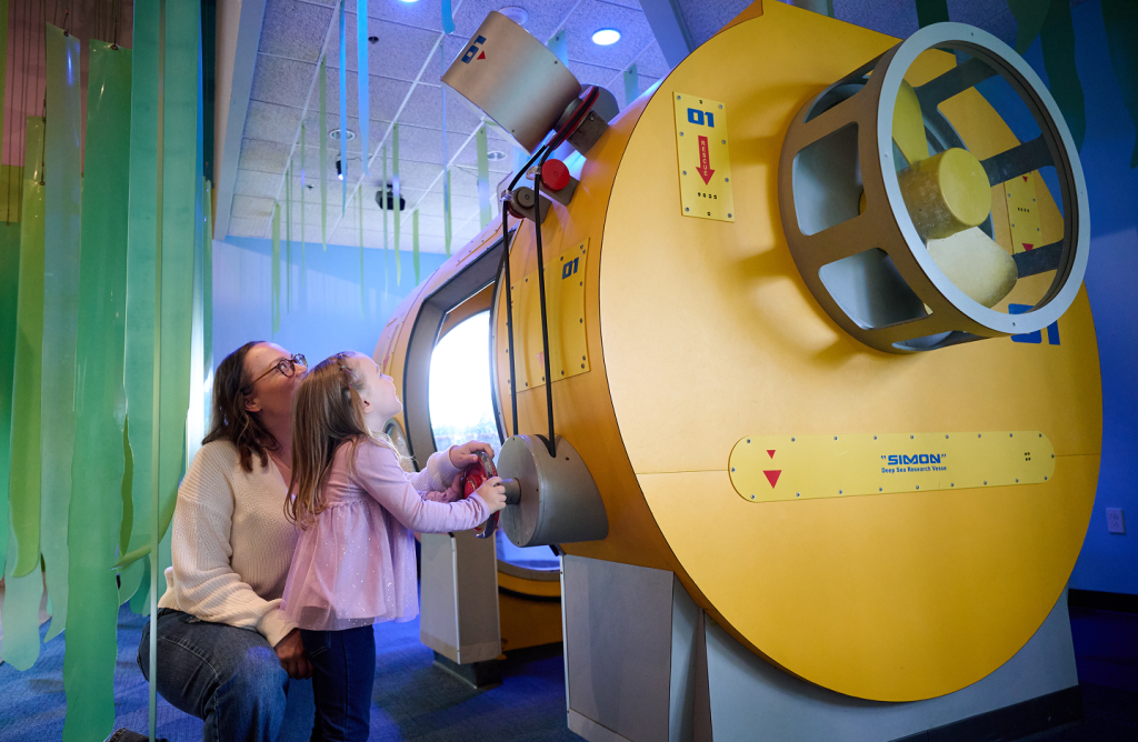 A small child and her mom interact with an exhibit in the Little Learner Clubhouse.