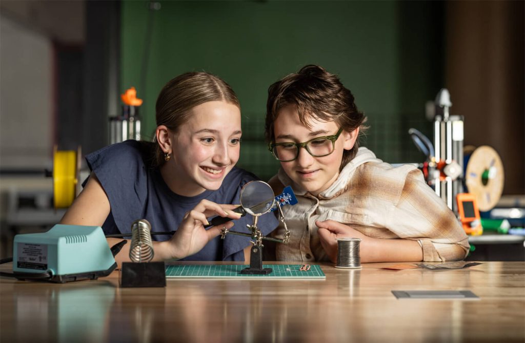 Two girls soldering a circuit board