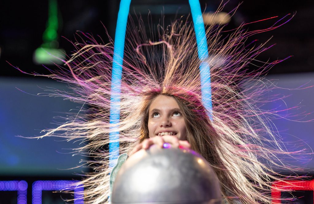 Young visitor touching a Van de Graaff generator