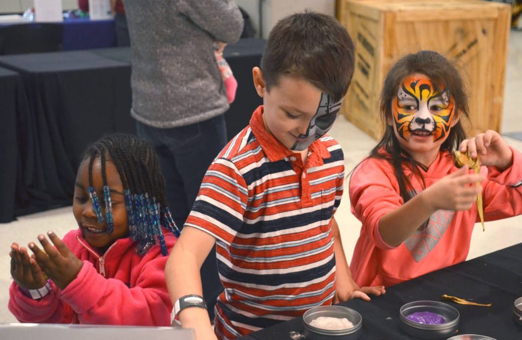 Children with facepaint on doing an activity.