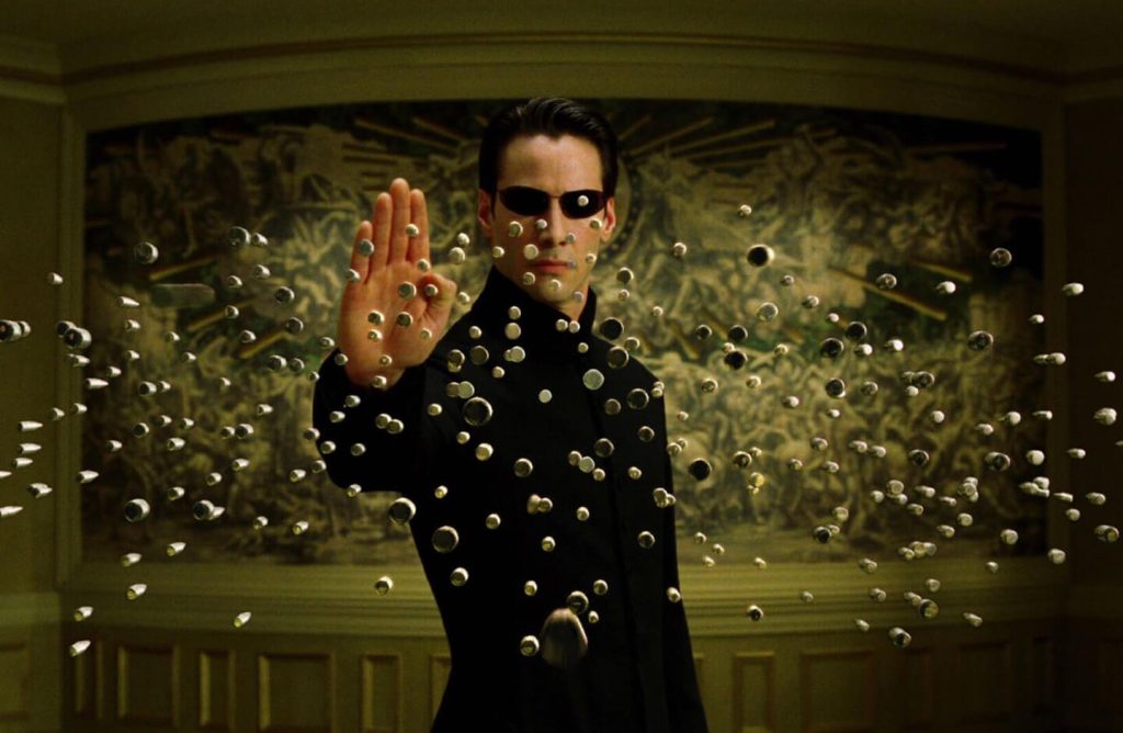A scene from The Matrix is shown: Neo is stopping bullets in mid-air.