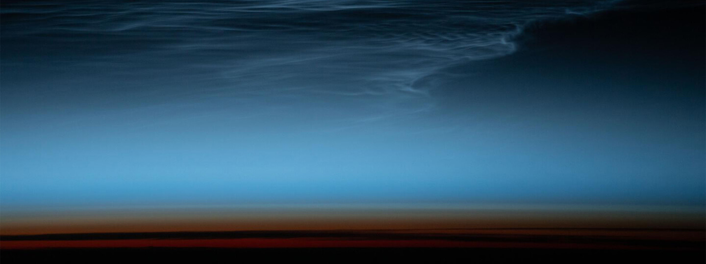 Wispy clouds in Earth's upper atmosphere illuminated by the sunlight just after sunset.