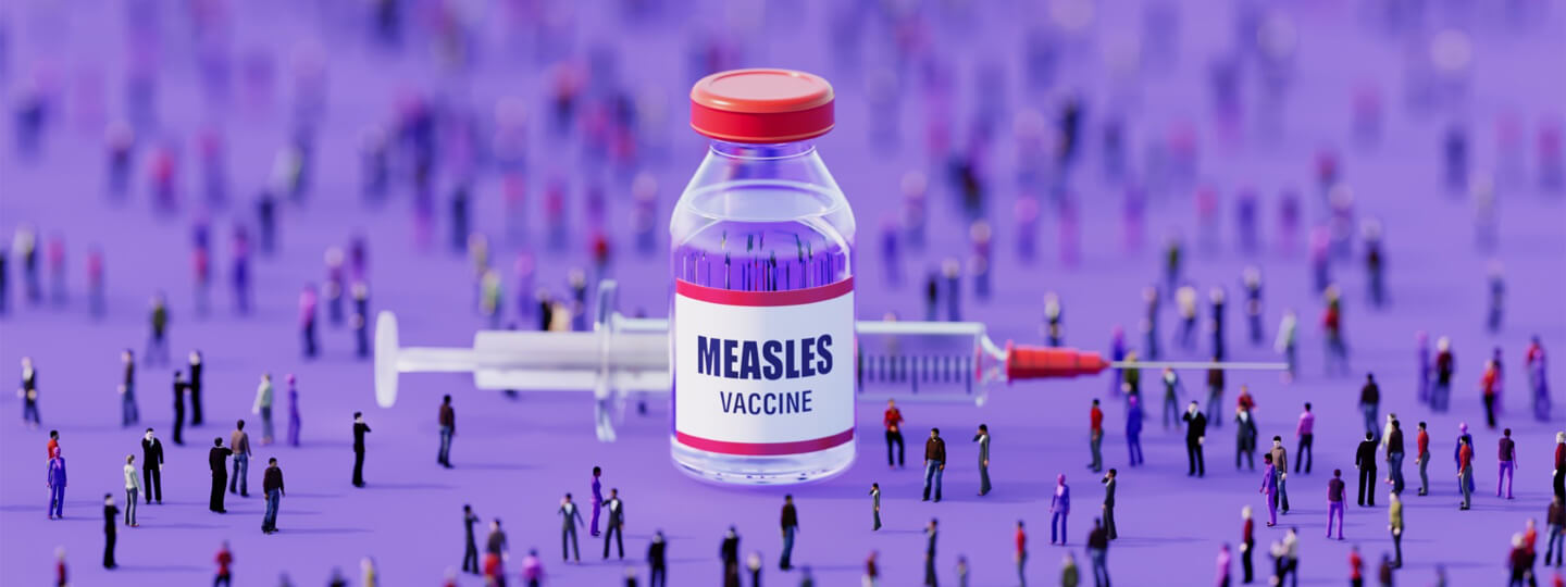 Large measles vaccine surrounded by miniature people figures.