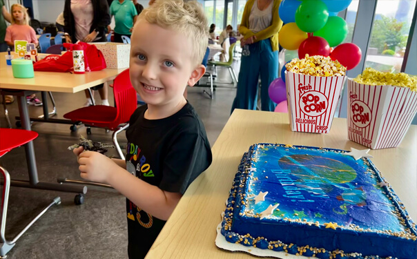 A boy at his birthday party with cake and popcorn