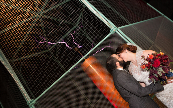 A bride and groom kissing next to the Tesla Coil