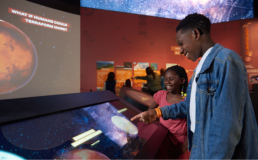 Teen volunteer interacting with visitor at exhibit display