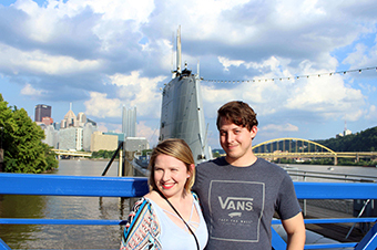 A couple in front of the USS Requin submarine with the city of Pittsburgh in the background