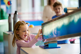 A smiling girl playing with a wave machine