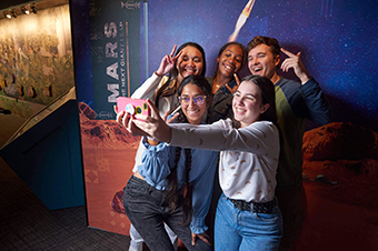A group of teens taking a selfie at the Mars exhibit