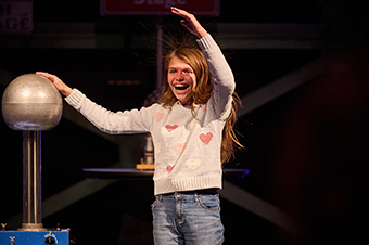 A girl touching a Van de Graaff generator