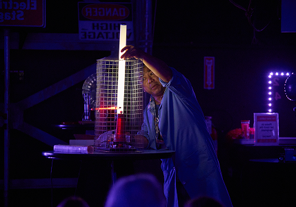 Adult on stage conducting a science experiment.