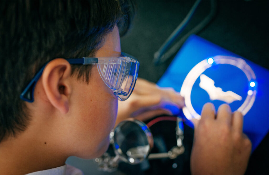 A boy wearing protective goggles and working on a project